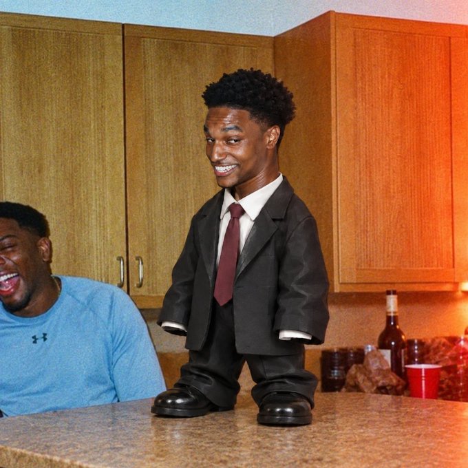 A photo featuring a large inflatable figure of basketball player Scottie Barnes in a suit, with a person laughing in the background in what looks like a kitchen setting.