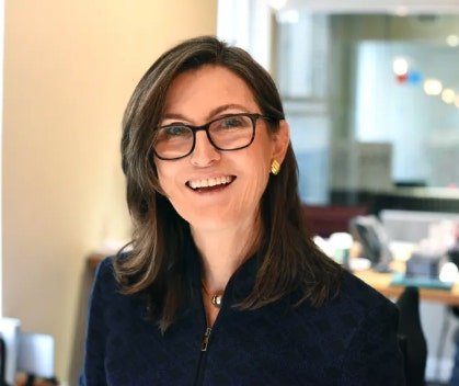 A professional headshot of Cathie Wood, the CEO of ARK Invest, smiling warmly in an office setting, accompanying an article about ARK Invest's significant profit-taking moves that involved selling large portions of its holdings in Coinbase, Circle, BitMine, and Bullish following a surge in crypto-related stocks.