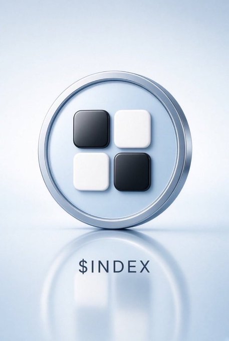 A glossy 3D silver coin featuring a 2x2 grid of black and white squares sits on a reflective surface, with the text '$INDEX' displayed below it.