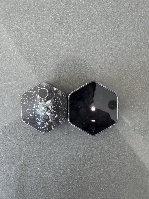 Two black hexagonal smart home devices, one with a speckled design and camera lens, the other a glossy screen displaying "BOB".