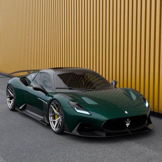 A dark green Maserati supercar parked in front of a yellow vertically-ribbed wall, featuring the trident Maserati logo.