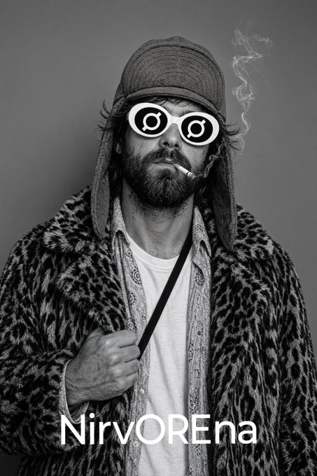 A black-and-white portrait of a bearded man wearing a flat cap, round novelty glasses, and a leopard print coat while smoking, labeled 'NirvOREna'.