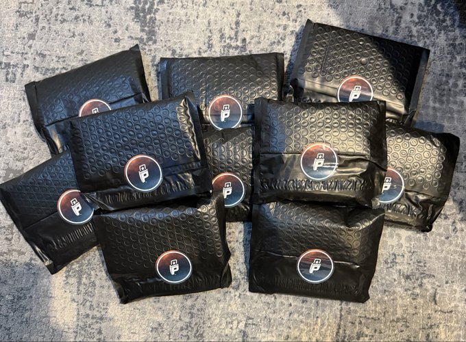 A pile of black padded shipping envelopes with a 'P' parking/lock icon logo, likely from a delivery or subscription service.