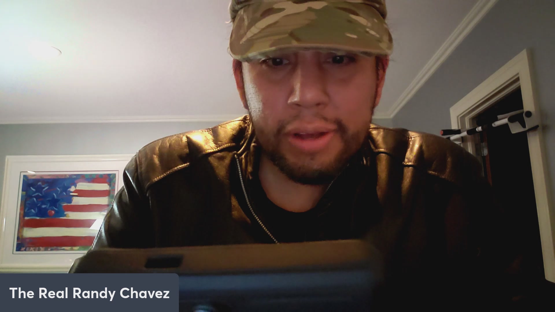 The image features a man wearing a camo hat, sitting down with his eyes focused on something outside of the frame. The caption reads "ROBLOX x VEVE! $OMI TO THE MOON!!". This suggests that the man is watching or engaging in an activity related to the game "ROBLOX" and possibly discussing it with someone else who is not visible in the image.