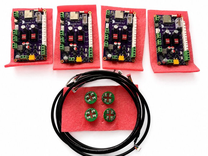 Four purple electronic circuit boards labeled 'SwarmBad V1.3' are arranged on red foam, with cables, small green sensor modules, and connectors in the center.
