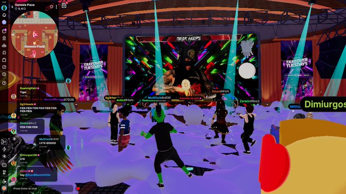 A screenshot from the metaverse platform Gather Plaza showing users' avatars gathered in 'Genesis Plaza' with 'TAKEOVER TUESDAYS' branding on screens and stage lights illuminating the scene.