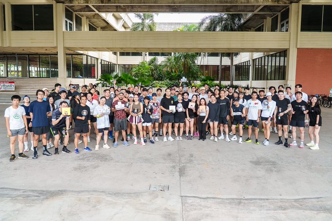 A large group of attendees poses together at the Pudgy Coffee Run x Bitkub Morning Meetup held at a venue in Bangkok, as promoted by Pudgy Penguins and Bitkub, celebrating the community gathering with everyone gathered smiling for the group photo.