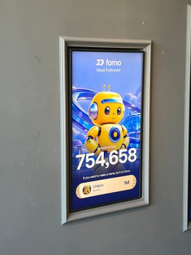 A framed poster displayed on a wall showcases a celebratory 754,658 follower milestone for the DJ Fomo "Most Followed" account, featuring a cartoon mascot character. The post expresses admiration for this achievement, suggesting the poster celebrates someone else's success that the user aspires to match.