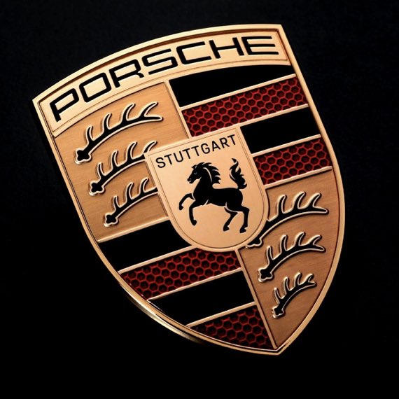 A close-up of a Porsche crest featuring the brand name, 'STUTTGART', and the iconic rearing horse emblem against a black background.