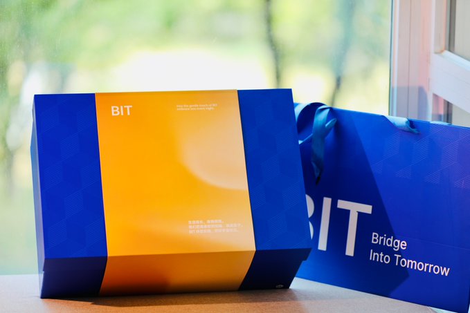 A blue and orange branded box labeled 'BIT' sits next to a matching blue shopping bag reading 'BIT Bridge Into Tomorrow.'