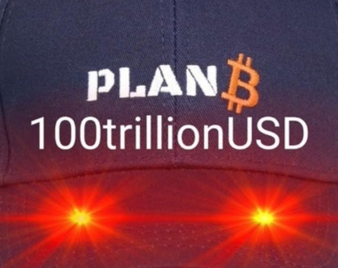 A close-up of a baseball cap reading "PLAN₿ 100trillionUSD" with two red lights below, mocking the Bitcoin price prediction of prominent analyst PlanB and his stock-to-flow model, which the post criticizes for leading followers astray with unrealistic projections.
