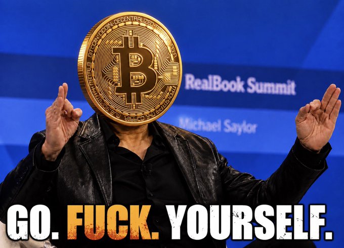 A man wearing a black leather jacket stands on stage at the "RealBook Summit" with a large gold Bitcoin prop covering his face, raising both hands. Bold text reading "GO. FUCK. YOURSELF." appears at the bottom, with his name "Michael Saylor" visible on the backdrop. The image pairs with the post's defiant message about Bitcoin holding near $76K despite a failed Clarity Act and an interest rate hike, echoing Saylor's well-known "Have Fun Staying Poor" attitude toward critics.