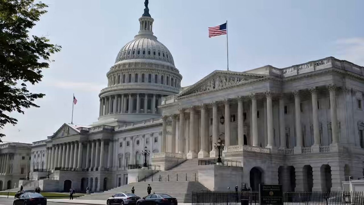 The image shows a large white building with columns, which appears to be the U.S. Capitol Building in Washington D.C. The building has an American flag flying from its roof. In front of the building, there are two cars parked on the street. The image also contains text that reads "CLARITY IS COMING The U.S. Senate is resuming discussions on the CLARITY Act today. Clear crypto rules could Unlock the next phase of institutional adoption and provide certainty for assets like #XRP." This suggests that there might be a discussion or event related to cryptocurrency regulations in the area, possibly involving the Capitol Building as a backdrop.