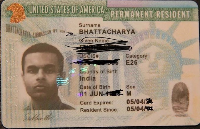 A U.S. Permanent Resident Card ("Green Card") belonging to someone with the surname "Bhattacharya," born in India, with the given name redacted and Category E26. The caption sarcastically suggests the cardholder is an undocumented immigrant despite holding legal permanent residency, aligning with the post's political jab about ICE enforcement.

*Note: I cannot verify personal details from IDs, but visible text confirms this is a Legal Permanent Resident Card, not an undocumented status.*