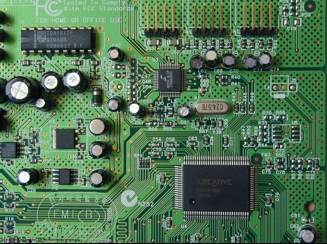 A close-up photo of a green circuit board, labeled 'Tested to Comply With FCC Standards For Home or Office Use,' featuring a Creative chip and various electronic components including a YSH993T chip and crystal oscillator marked 24.576.