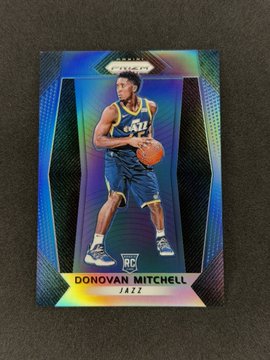 A holographic Prizm basketball trading card features Donovan Mitchell in his Cleveland Cavaliers uniform, labeled 'RC' (Rookie Card) and 'DONOVAN MITCHELL.'