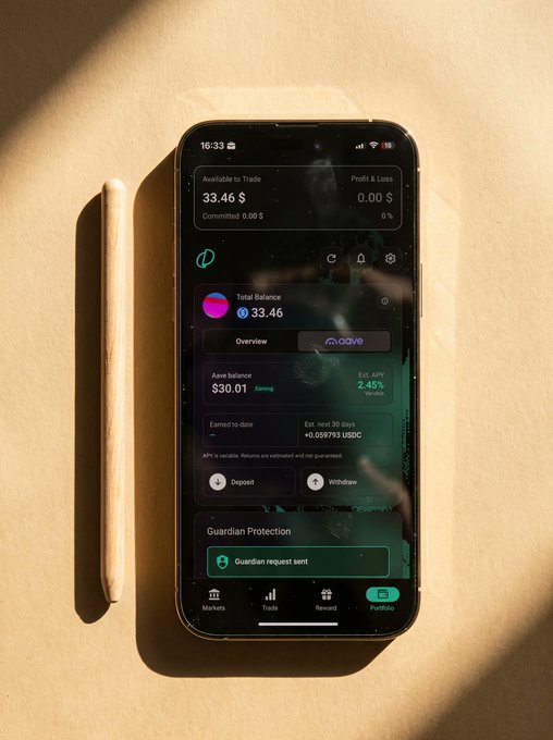 A smartphone lying on a beige surface displays a dark-themed crypto trading app with balances, market, deposit, and withdraw options; visible text includes “Available to Trade 33.46 $” and “Guardian Protection.”
