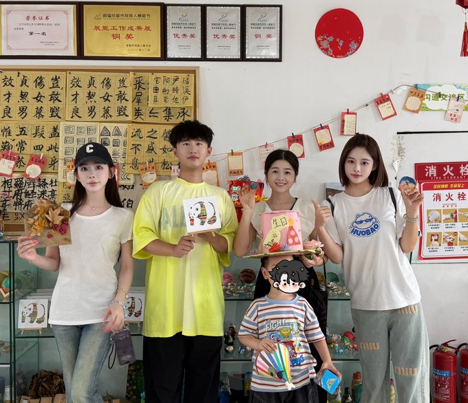 Under plaques recognizing Luyao as a "Caring Entrepreneur" and behind calligraphy reading "愿天下小孩都成栋梁" (May all children become pillars of society), the HTX DAO team gathers with a child whose face is covered by a sticker, holding a small birthday cake and gifts—visually embodying the group's quiet, hands-on approach to youth-focused community welfare.