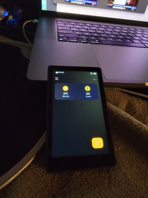 A smartphone displaying the Zashi wallet app with BTC (Bitcoin) and ZEC (Zcash) options sits in front of a laptop, illustrating the post's message about using Zashi to shield ZEC holdings for on-chain privacy. The wallet interface directly references the recommended Zashi app mentioned in the reminder about protecting Zcash assets.