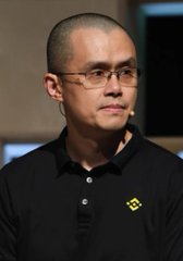 A man with a shaved head wearing glasses and a black polo shirt with a Binance logo on the chest.