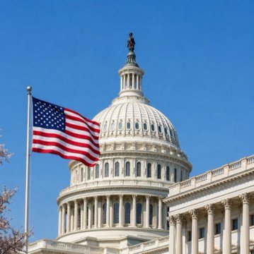 The U.S. Capitol building dome is shown against a clear blue sky with the American flag flying prominently in the foreground.