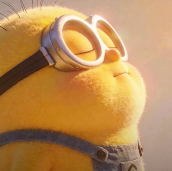 A close-up of a yellow minion character wearing aviator goggles and denim overalls, shown in profile looking to the side with a contemplative expression. The image humorously pairs with the post's question about crypto trading, using the minion's upward gaze as a visual stand-in for someone being accused of being "the mf responsible" for high-performance trading pairs.