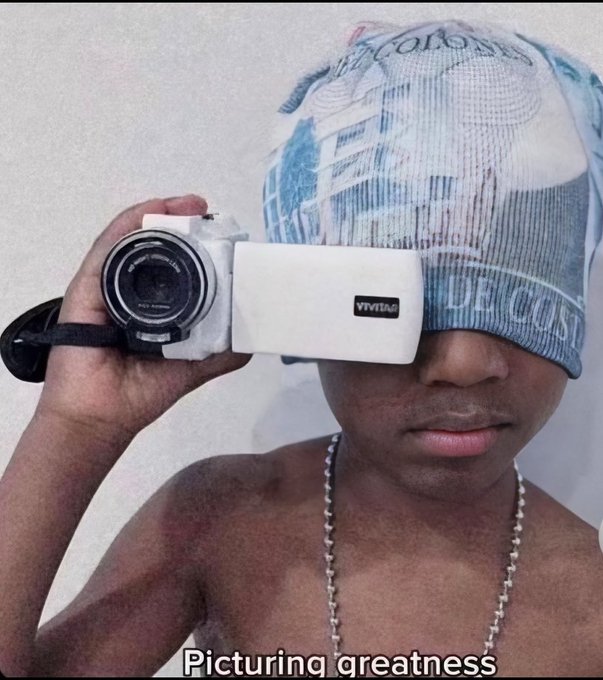 A shirtless young man takes a selfie in the mirror, wearing a blue and white patterned durag and a silver chain, while holding a white Vivitar camera up to his eye. The caption "Picturing greatness" plays on the camera visible in the image, fitting the post's casual Thursday afternoon greeting to his followers.
