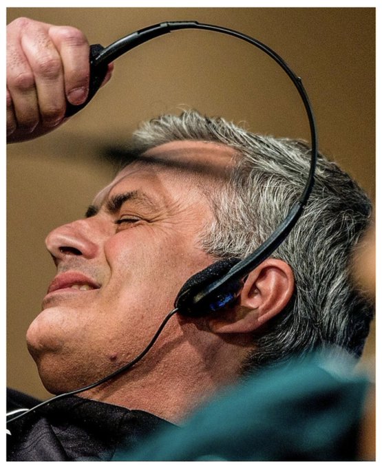 A photograph of Federal Reserve Chairman Jerome Powell appearing to remove or place a headset on his head, with his eyes closed.