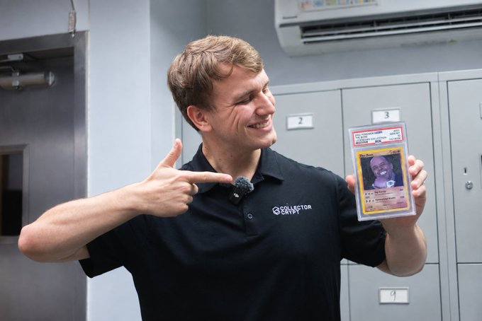 A smiling man wearing a "Collector Crypt" black polo shirt points proudly at a graded Pokémon card of Mime Jr. (HR 90/108), connecting to the "Collector Crypt" meme format being promoted in the post. The setting appears to be behind a bank of numbered safety deposit boxes, reinforcing the collectibles vault aesthetic of the brand.