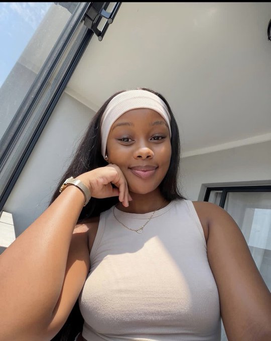 The image features a woman with long hair wearing a white headband, posing for a photo. The background of the picture includes a window that allows natural light into the room. There are also some texts visible in the image, which seem unrelated to the main subject and do not provide any additional information about the post or its content.