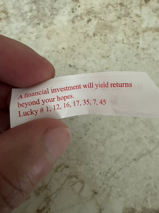 A hand holds a fortune cookie slip reading "A financial investment will yield returns beyond your hopes. Lucky # 1, 12, 16, 17, 35, 7, 45," which the poster jokingly cites as a "bullish signal" ahead of Bitcoin's potential all-time highs.