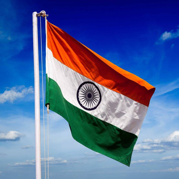 The Indian national flag waves against a bright blue sky, featuring its horizontal tricolor bands of saffron, white, and green with the navy blue Ashoka Chakra in the center. The image relates to the post by symbolizing India, where surging USDT premiums reflect heightened demand for stablecoins amid regulatory pressure on crypto remittance services.