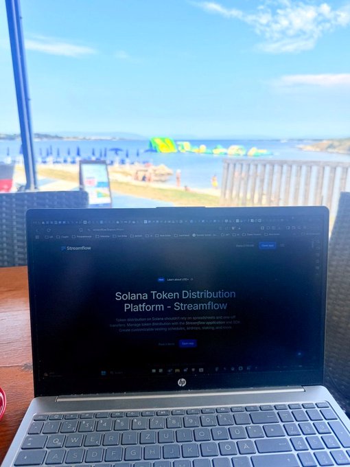 An HP laptop sits on a wooden table displaying the Streamflow website ('Solana Token Distribution Platform'), with a scenic ocean and beach view in the background.
