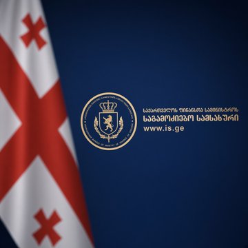 The image displays the emblem of Georgia's Investigation Service alongside the Georgian flag, featuring the agency's website "www.is.ge" in both Georgian and English script. This visual accompanies news that the Investigation Service arrested an unregistered virtual asset service provider (VASP) manager, seizing crypto, bank cards, and cash tied to tens of millions of dollars in unregistered transactions.