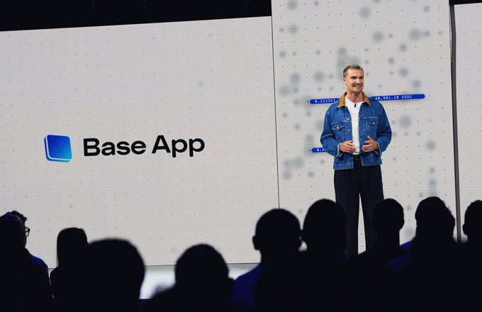 A presenter in a denim jacket stands on stage at a Coinbase Base App event, with the "Base App" logo displayed prominently on the large screen behind him as he addresses the audience about the Beryl upgrade and the new B20 token standard.