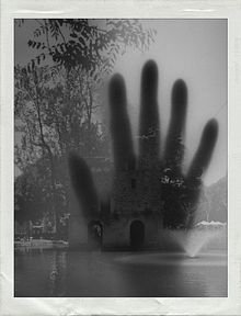 A black and white photograph showing a large handprint superimposed over a misty lake scene with trees, with handwritten text '09/02/2017'.