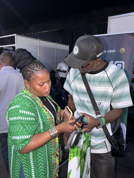 A woman in a green patterned outfit with intricate braids and a man in a white cap and striped shirt are seen looking down at a phone together at what appears to be the NFT__NG event. The two stylish attendees seem engaged in conversation while examining content on the device, likely networking or sharing event-related information in line with the post's theme of meaningful connections made at the gathering.