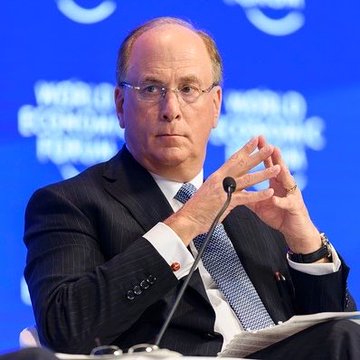 A man in a dark suit and glasses gestures with his hands while speaking at a panel, with a blue backdrop partially displaying "WORLD ECONOMIC FORUM" behind him. The image is relevant to the post as it likely depicts a BlackRock executive, such as Larry Fink, whose firm's clients have purchased $64.68 million worth of Ethereum.
