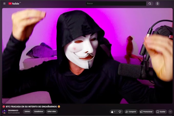 A YouTuber wearing a white Anonymous-style mask and black hoodie records a video titled "BTC FRACASA EN SU INTENTO DE ENGAÑARNOS" (BTC fails in its attempt to deceive us) by channel "GRANMAGO" with 263K subscribers, promoting a crypto market update covering BTC, oil, gold, silver, $SPCX, and altcoins on the 1H-4H-1D timeframes.