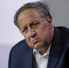 Adam Aron, CEO of AMC Entertainment, is shown with a serious, contemplative expression while wearing a dark suit and white shirt, reflecting his critical stance on Robinhood's tokenization of AMC shares described in the accompanying post.