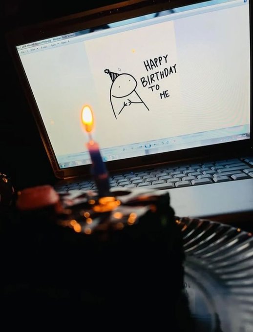 A birthday cake with a single lit candle sits in front of a laptop displaying a MS Paint drawing of a stick figure with a party hat and the text 'HAPPY BIRTHDAY TO ME'.