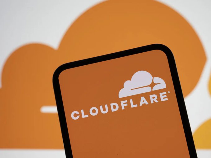 The Cloudflare logo, featuring its signature orange cloud design, is displayed on a smartphone screen against a matching orange backdrop. This visual ties into the announcement of Cloudflare's new AI agent payment system, which leverages fractional stablecoins and Coinbase's x402 gateway to enable autonomous API and content transactions without account setup.