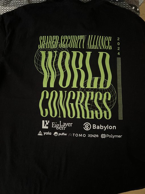A black t-shirt features neon green graphic text reading "SHAPED SECURITY ALLIANCE" and "WORLD CONGRESS 2024" with globe illustrations, along with sponsor logos including EigenLayer, Babylon, Yala, Puffer, TOMO, RENZO, and Polymer.