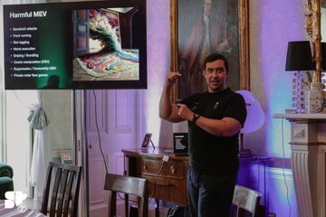 A man giving a thumbs-up in a lavishly decorated room with purple lighting and artwork, with an overlaid slide titled 'Harmful MEY' listing types of harmful interactions in AI.