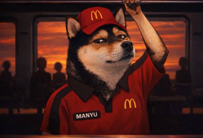 A Shiba Inu dog wearing a McDonald's uniform with a name tag reading 'MANYU' grips an overhead bar inside what appears to be a bus or train at sunset.