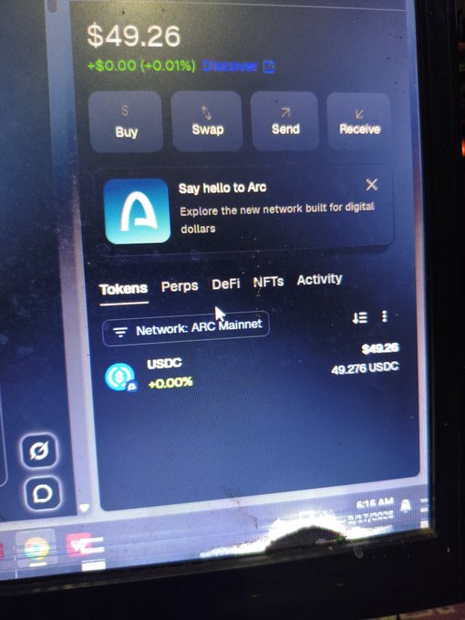 A photograph of a computer screen showing a cryptocurrency wallet interface with a balance of $49.26 USDC on the ARC Mainnet network, featuring buttons for Buy, Swap, Send, and Receive.