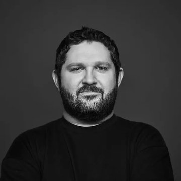 The image shows a black-and-white portrait of a bearded man with curly hair wearing a dark shirt, photographed against a plain background. The photo appears to be a professional headshot, likely representing Alex Thorn, the Galaxy Digital figure referenced in the post about his critical comments on BIP-110.