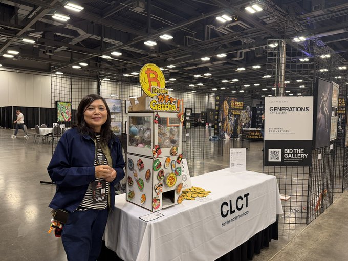 A woman standing next to a prize claw machine filled with donuts at a CLCT (Clear Lake Community Theatre) table at an indoor convention.