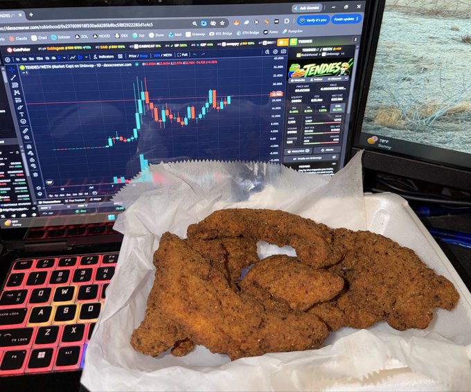 A basket of fried chicken tenders sitting on a napkin in front of a laptop displaying a CoinPulse trading chart for DOGE/USDT Perpetual.