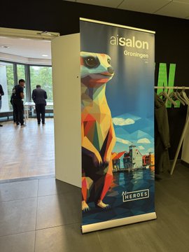 A vertical banner for 'ai salon Groningen' featuring a colorful geometric illustration of a gecko, with a 'HEROES' logo at the bottom, displayed indoors.
